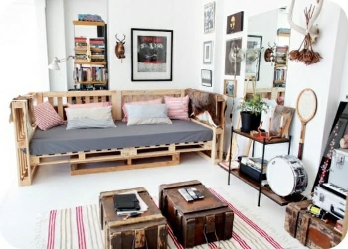 Ambiente arredato con divano v paleti, valigie vintage utilizzate come tavolini