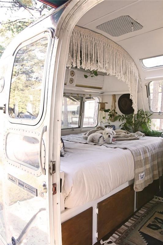 makrome perde ahşap yatak ile donatılmış küçük kamyonet koyu parke gri halı çizgili desenler bej yatak ve gri bitkiler atmak