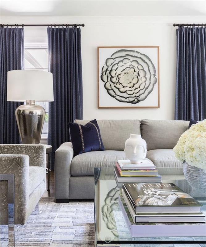 açık gri kanepe, koyu mavi perdeler, cam sehpa ve gri koltuk ile modern oturma odası düzeni