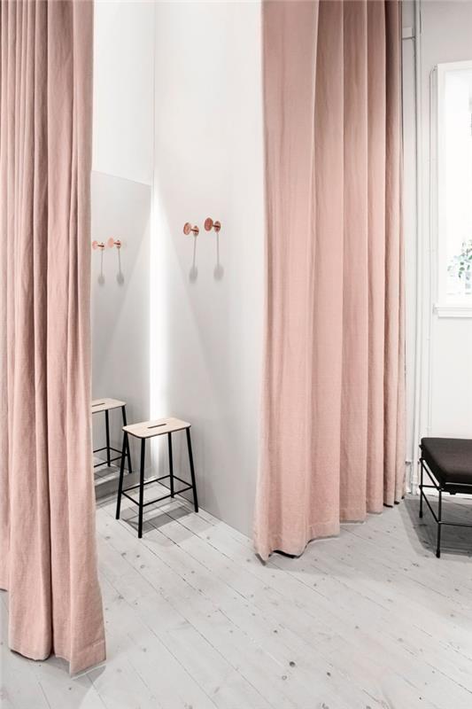 moderni interjero puošmena su baltomis sienomis su ilgomis rausvomis rožinėmis užuolaidomis ir medine bei matine juoda išmatomis