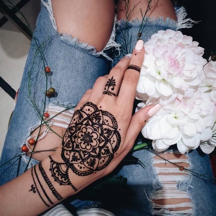 velika tetovaža s kano, roza lak za nohte, tetovaža levjih prstov, roka, ki drži cvetlični šopek