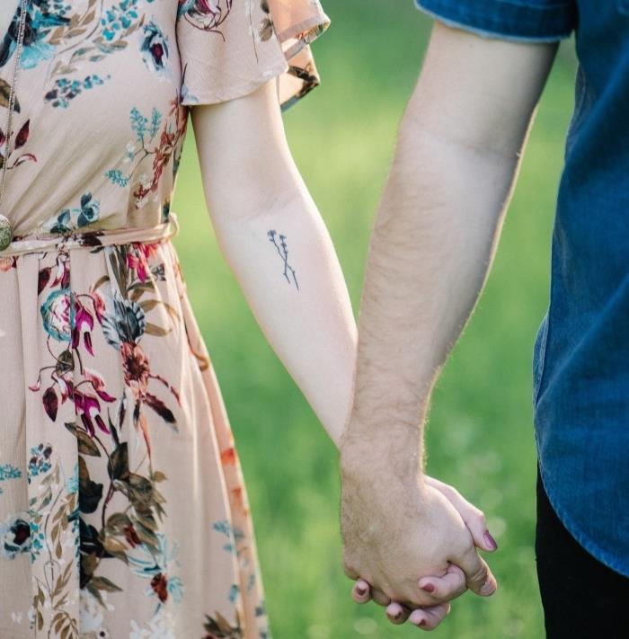 model majhne ženske tetovaže s cvetličnim in minimalističnim dizajnom, ženska oblečena v bež obleko z majhno tetovažo na roki