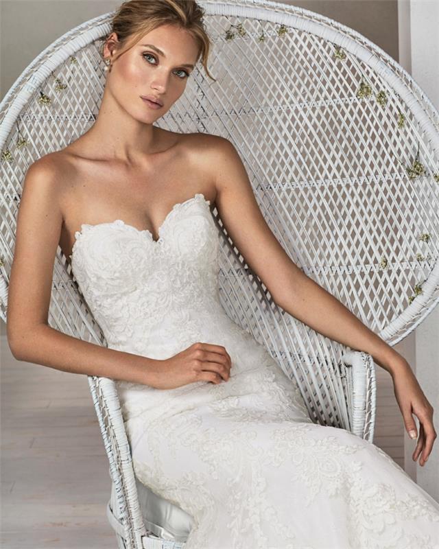 undinė vestuvinė suknelė su krūtine, balti nėriniai, nuotaka, sėdinti balto rotango fotelyje su labai plačia vėduoklės tipo nugara, undinė vestuvinė suknelė