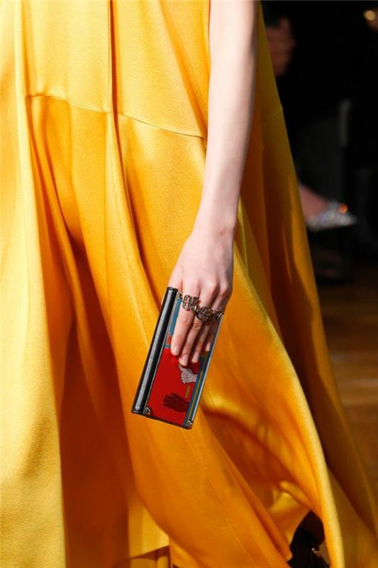 dolga in tekoča oranžna obleka, brez rokavov, iz satenastega materiala, mikro torbica v rdeči in črni barvi, eleganten večer s šok detajli