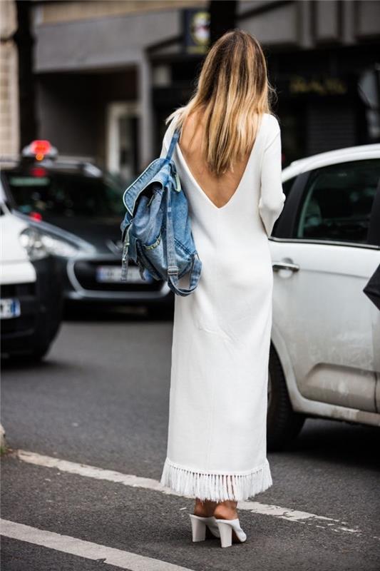 denim sırt çantası ve açık ayakkabı ile süslenmiş sırtı açık ve uzun kollu beyaz uzun elbise örneği