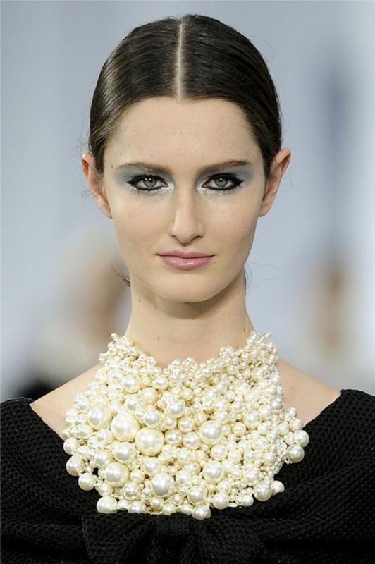Chanelov videz, masivna ogrlica z biseri, velike kroglice na vratu, dragulj, oblečen čez črno obleko z velikim lokom, ki je viden pod biserno ogrlico