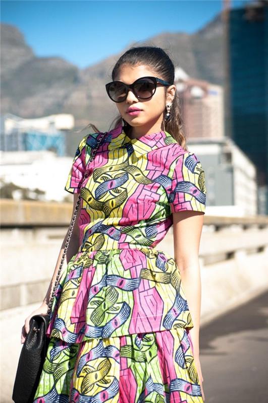 šiuolaikiška afrikietiška suknelė su marškinių apykakle su žalios, rožinės ir geltonos spalvos vaško raštais, suteikianti prašmatnų ir gaivų vasaros vaizdą