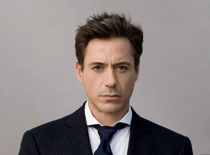 genç bir robert downey jr, ince çizgili bir takım elbise giymiş, beyaz bir gömlek ve siyah bir kravat takmış, kısa, esmer bir ekip kesimi giymiş