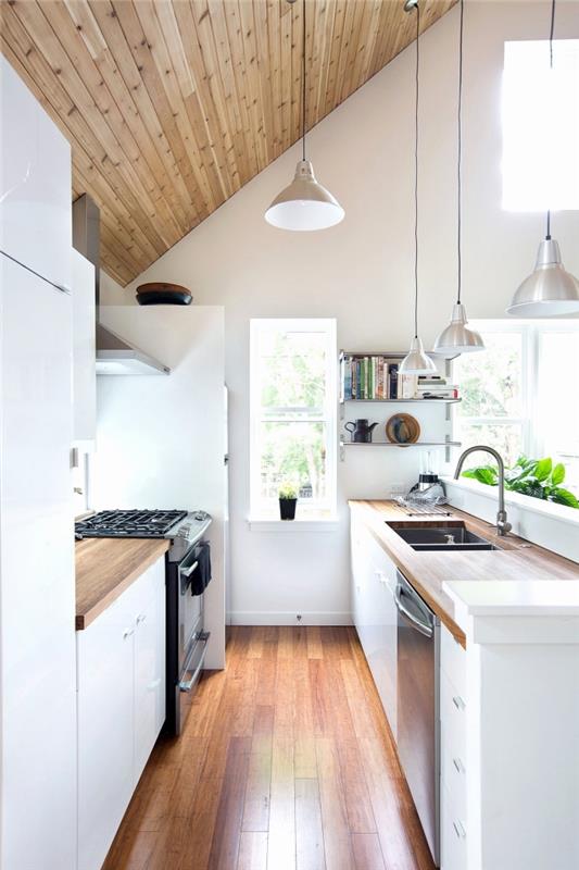 minimalistični slog v kuhinji z belimi stenami s stropom in leseno talno oblogo ter industrijsko razsvetljavo