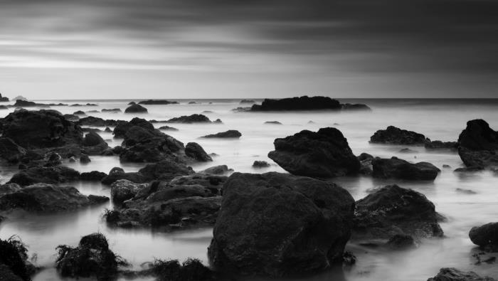 črno -bela fotografija skalnate plaže v megli, morske pokrajine, prežete z določeno mistiko