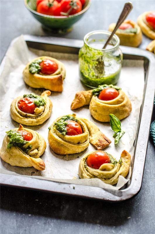 Ortasında kırmızı kiraz domates ve ev yapımı pesto, aperatif akşam yemeği fikirleri olan küçük puf böreği şeritleri için salyangoz tarifi