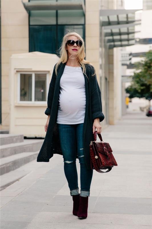atsitiktinio stiliaus nėštumo apranga džinsuose ir palaidinėje su ilgu megztiniu, nėščios moters drabužių idėja, vyno lovos rankinės modelis