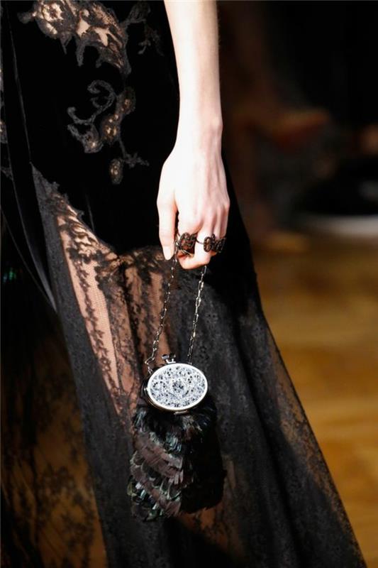 črna čipkasta večerna obleka z arabeskami na pasu, mini torbica v vintage stilu v perju in velika srebrna zaponka, elegantna in šokantna tema