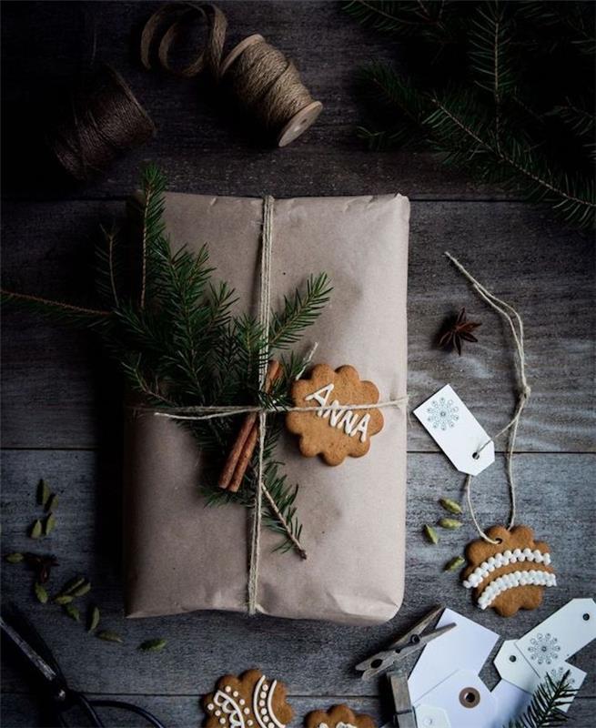 kraft maišelis kaip dovanų įpakavimas, su cinamono puošmena, pušies šakomis ir imbiero kalėdiniais pyragais