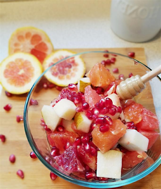 vaisių salotos su medumi, greipfrutais, stikliniu dubeniu, šaukštu medaus, kriauše, pomelo