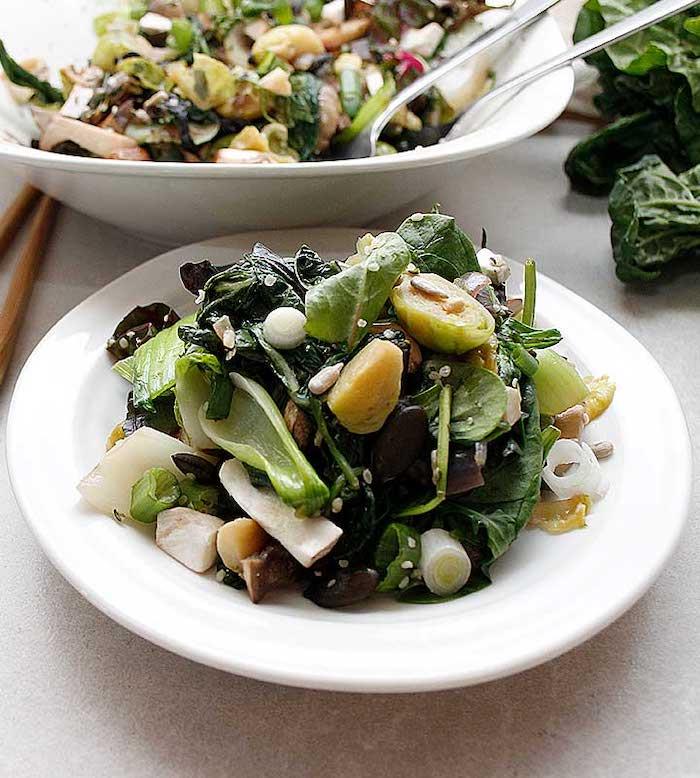 kvinojos salotos su špinatais ir endivuoti du pilni dubenėliai su azijietiškomis lazdelėmis šalia žieminių salotų