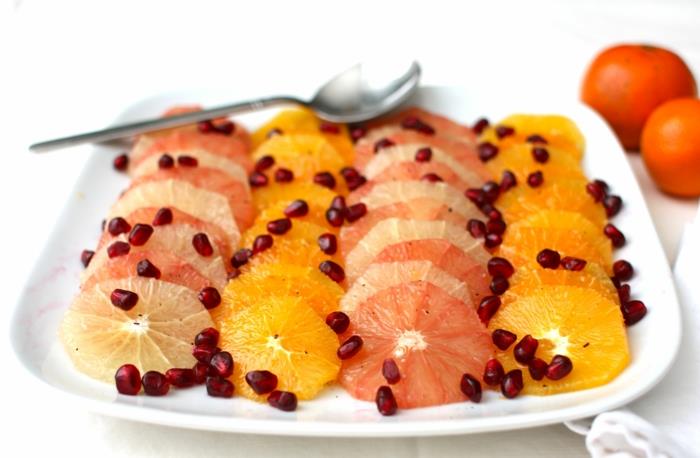 citrusinių vaisių salotos su granatų sėklomis, keturios eilės vaisių vienoje baltoje lėkštėje