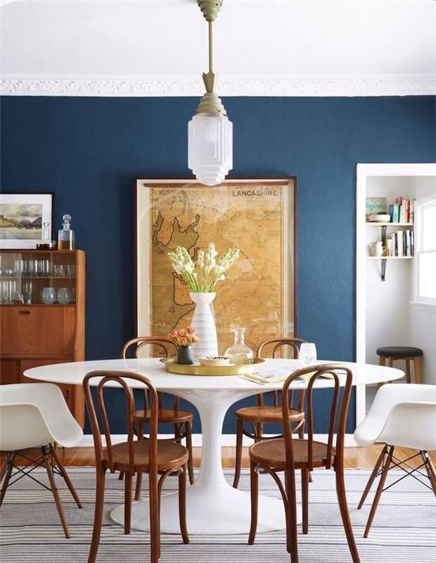 bela jedilna miza, obdana z lesenimi stoli, modre stene, z dekoracijo starinskega zemljevida sveta, predalnik iz starodobnega lesa, parket iz svetlega lesa