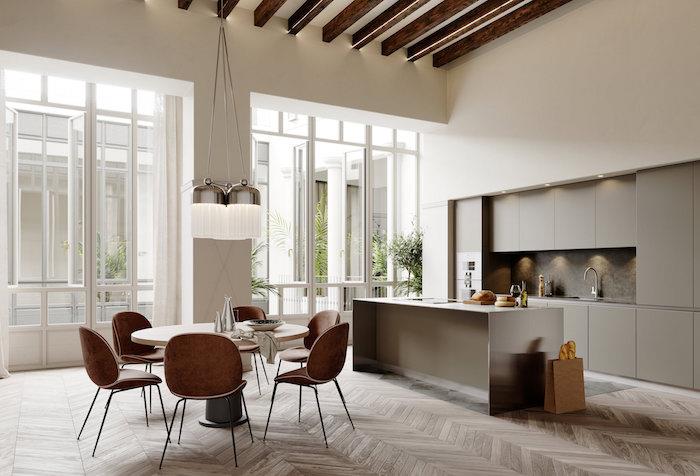 popolna oblikovalska jedilnica z odprto kuhinjo in sivim otokom na lesenih tleh z retro stoli in belimi stenami