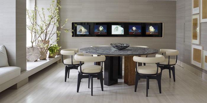 razkošna jedilnica z okroglo mizo in bež usnjenimi stoli ter sivimi stenami