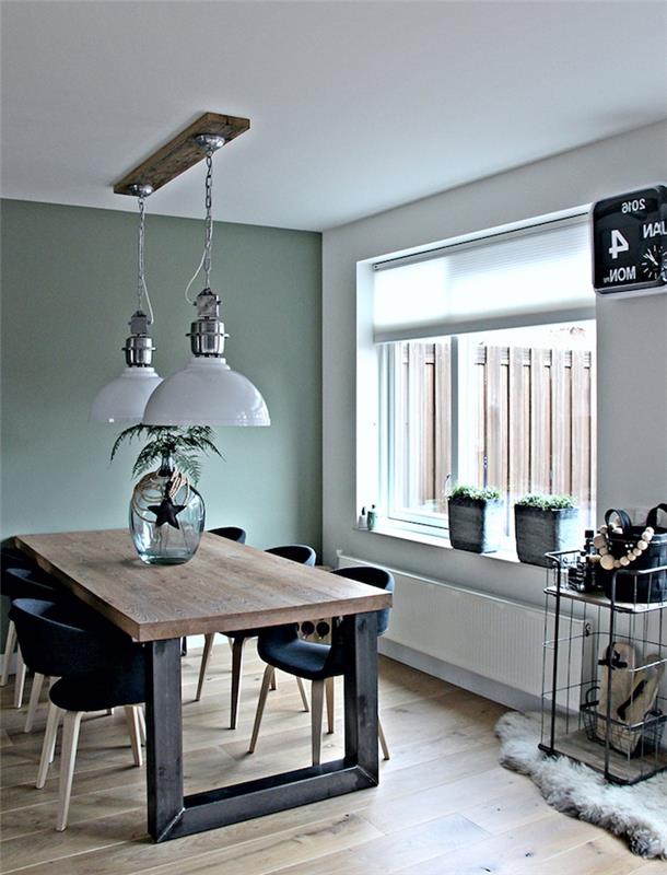 Komplet zelene jedilnice Celadon, lesena in črna kovinska miza, črni skandinavski stoli, svetel parket, zelene rastline in viseče svetilke v industrijskem slogu