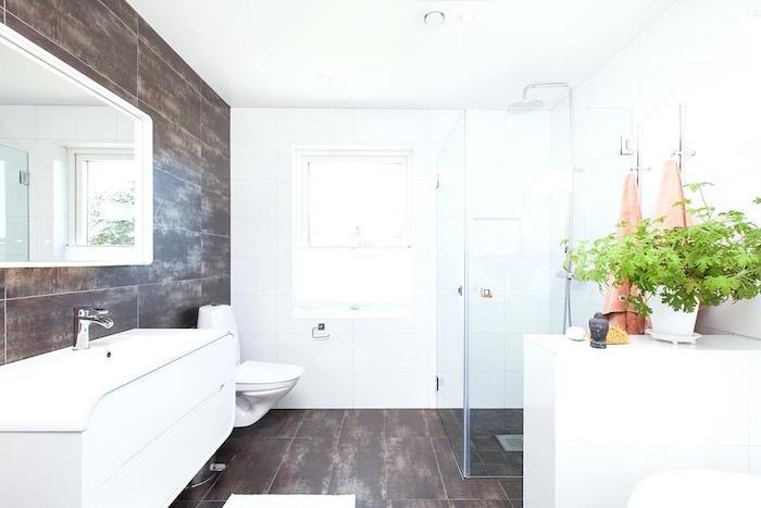 odprta kopalnica z italijansko prho s keramičnimi stenami in rjavimi tlemi ter belimi stenami z okrasjem zelenih rastlin