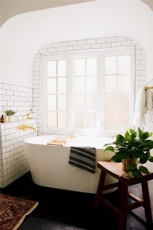 globoko bela samostojna kad v kopalnici z velikim oknom in steno iz norveških belih ploščic