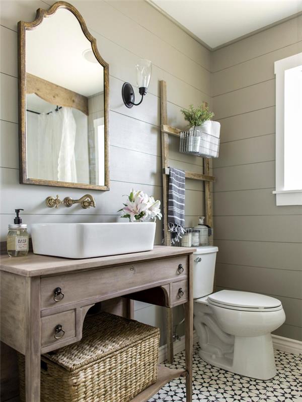 toplo in sproščujoče vzdušje v stari kopalnici s ploščicami, opremljeno s toaletnim ohišjem iz starinskega lesa