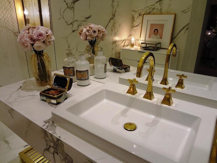 vonios kambarys su auksine kriaukle ir gėlių vaza šalia