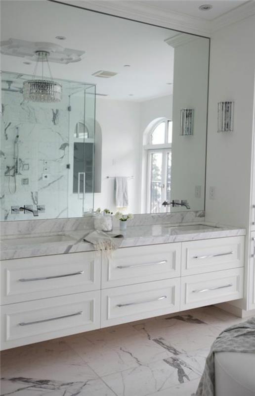 baltas vonios kambarys su dideliu veidrodžiu ir marmurinėmis grindimis baltos marmuro plytelės