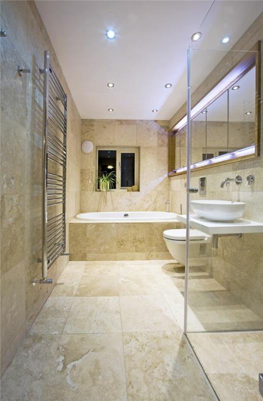 travertino vonios kambarys, stiklinės sienos, baltos lubos, įmontuota vonia