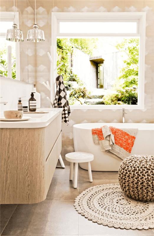 medinis vonios kambarys su pilkomis plytelėmis išklotomis grindimis balta vonia balta siena ir smėlio spalvos pilkos spalvos pufuotas pintas kilimas
