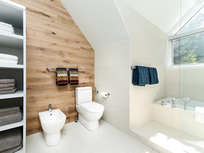 Skandinavska kopalnica z lesenim parketnim zidom in belimi ploščicami na tleh in stenah