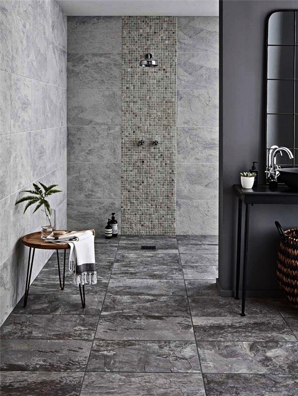 sodobna kopalnica v sivih ploščah in z rafiniranim dizajnom z diskretnim in odprtim tušem, ki se zlije z dekorjem