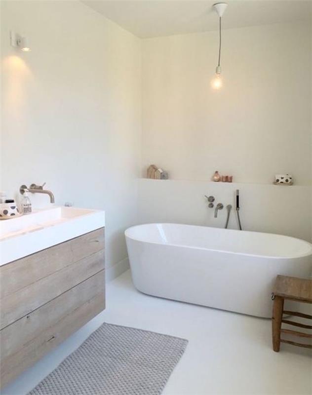 Minimalističen kopalniški dekor v skandinavskem slogu z belimi stenami in ovalno belo kadjo ter leseno omarico z velikim pravokotnim umivalnikom