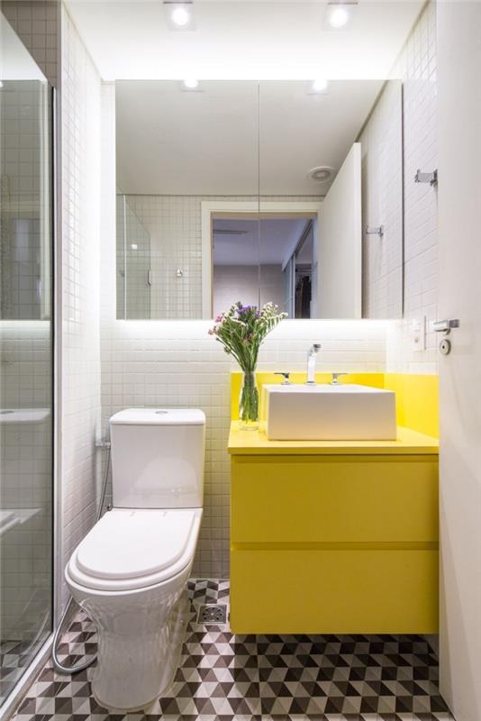 Ideja za postavitev kopalnice v majhnem prostoru z belo tuš kabino in rumeno omaro s shrambo