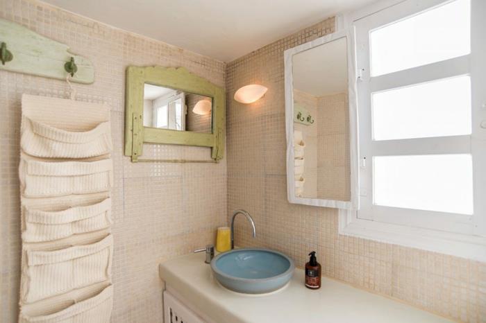 Grška kopalnica, bele ploščice, modri umivalnik, ogledalo z okvirjem iz lesa kaki