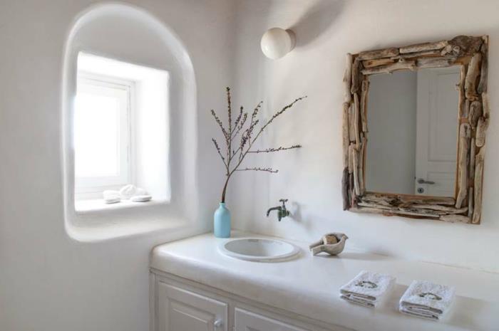 Grška kopalnica, majhno belo okno, ogledalo z vejicami, suho cvetje, pomivalno korito iz marmorja