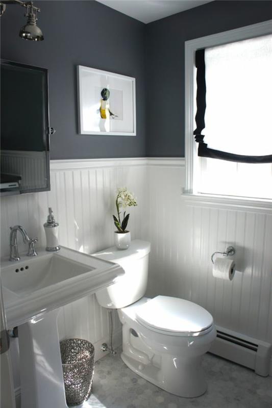 mažas baltos ir pilkos spalvos vonios kambarys su vintažiniais elementais ir baltos bei spalvų stalas