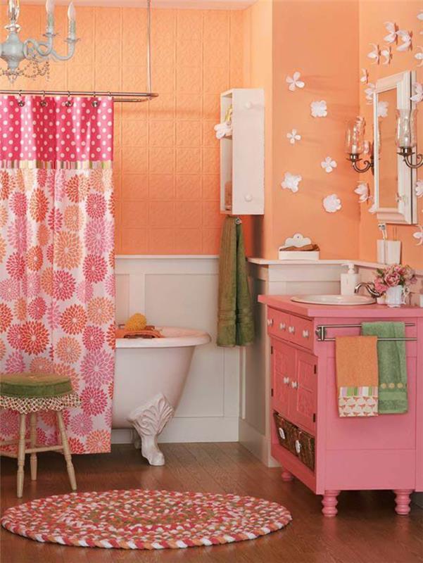 majhna kopalnica z breskovimi in rožnatimi stenami ter cvetličnimi in pikčastimi zavesami baročni lestenec na stropu