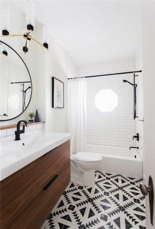 mažas vonios kambarys su dideliu apvaliu veidrodžiu su plonu metaliniu juodos spalvos rėmu