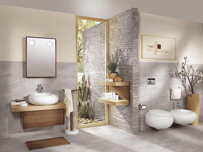 vonios kambarys iš natūralaus akmens ir šviesiai medinės sienos smėlio ir pilkos spalvos akcentais