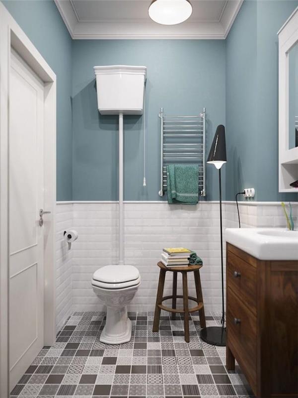 kopalnica v majhnem prostoru s straniščem s sivimi ploščicami in steno z belimi ploščicami ter omarico iz temnega lesa