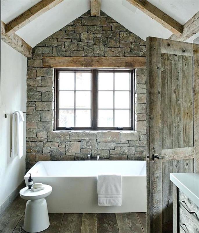 senas vonios kambarys atnaujintas senais pilkais akmenimis, parketo grindimis ir senovinėmis medinėmis durimis