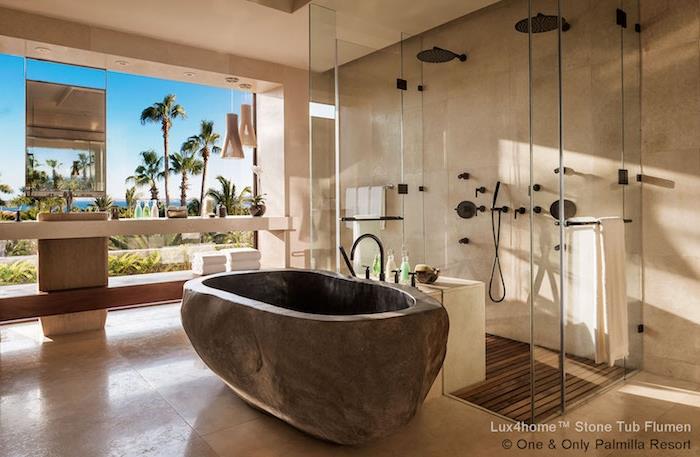modernus smėlio spalvos travertino vonios kambarys su natūralaus akmens vonia su vaizdu į jūrą