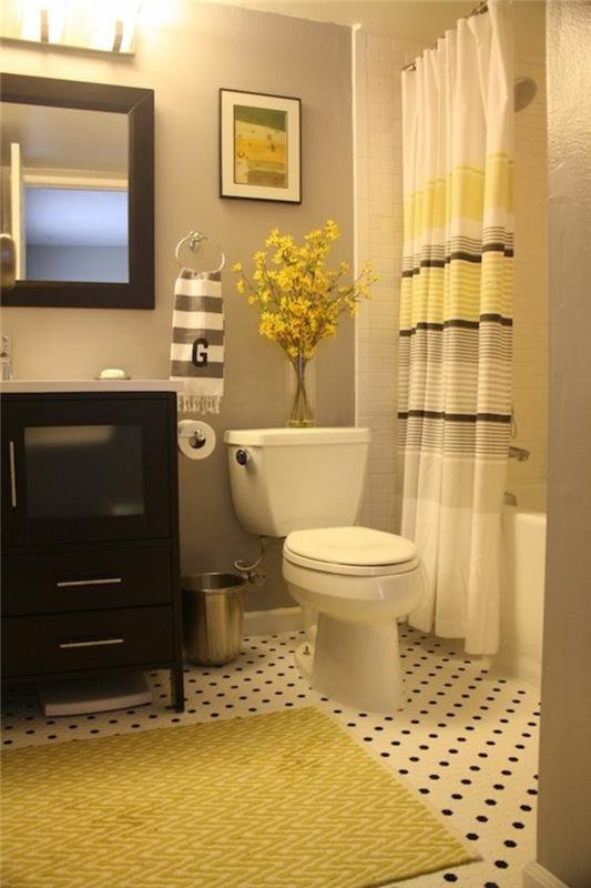 mažas vonios kambarys su baltomis užuolaidomis su geltonomis ir rudomis juostelėmis su geltonais kilimais juodais baldais