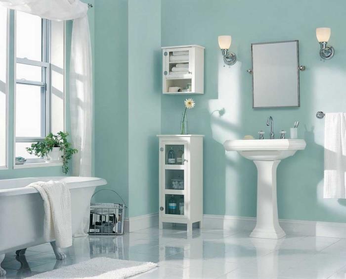 pastelinė žalia vandens siena vonioje, balta grindų danga ir balta vonia ant stalviršio, konsolinė kriauklė