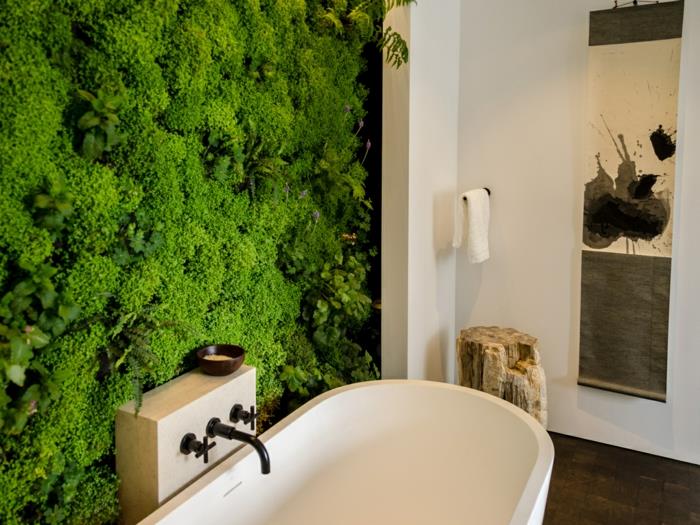 vonios kambarys be šviesos, siena su žalios samanos augmenija, laipiojimo augalas patalpoje, baltos sienos, medžio kamienas kaip dekoratyvinis objektas kampe