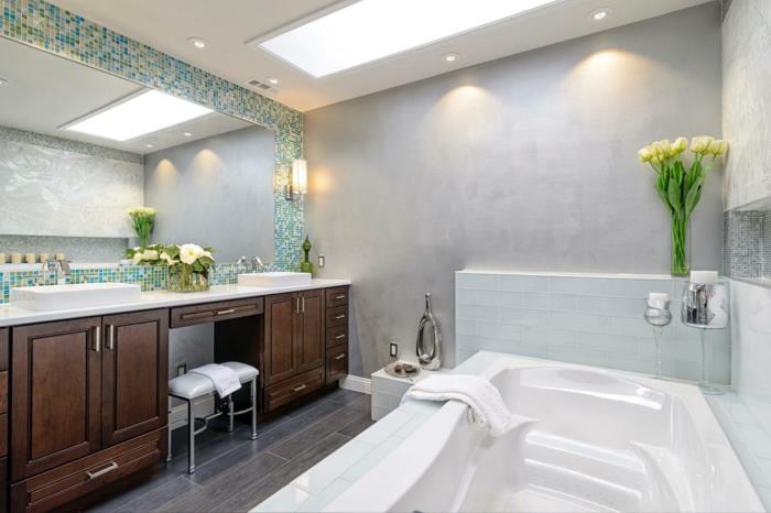 vonios kambarys, kambariniai augalai, žalias vonios kambarys, pilkos plytelių plokštės, imituojančios parketo efektą, tamsiai rudi baldai ir balto paviršiaus viršus, SPA stiliaus vonia su vandens masažu