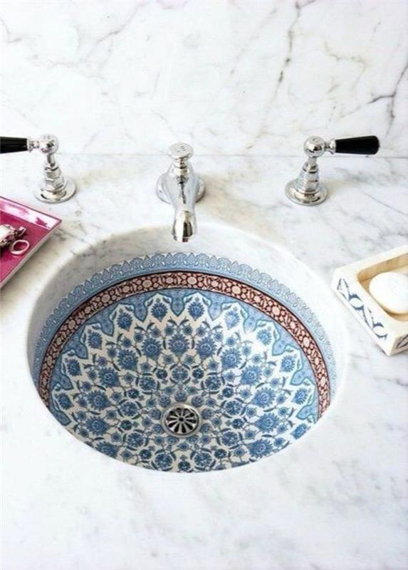 pinterest banyo, Arap tarzında mavi, beyaz ve turuncu desenlerle süslenmiş yuvarlak alt lavabo, gümüş renkli küçük lavabolar, ince siyah kaburgalı beyaz mermer yüzey planı